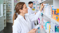 A pharmacist shown stocking medication on a shelf.