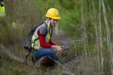 employee with hardhat squats in field