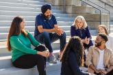 CEO Aman Bhutani shown with a group of people chatting on steps outside of a building.