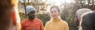 A person in a yellow-knit jumper talking to a group of people