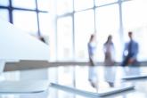 Blurred photo featuring three people in the back of a well-lit office space