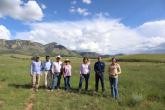 Boomitra staff and stand in a grasslands field with local ranchers 