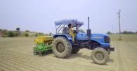 A person in a tractor doing over bare fields.