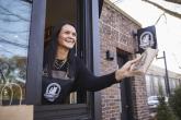 Kimberly Hoffmann leaning out a drive-thru window handing someone an item.