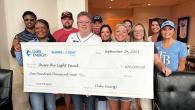 Groupd of people smiling while holding a cheque for $100,000