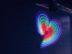 A rainbow heart in neon lights on a dark wall.