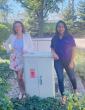 Two people posed next to an outdoor electrical box.