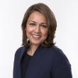 Brown haired lady smiling with a navy blue jacket.
