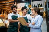 Three retail workers reviewing notes on a clipboard