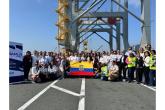 A large group of women and men stand together at a port terminal holding the Ecuadorian flag during a gender equity event with Red MAMLa.