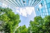 Bottom-up view of an office building and trees with a blue sky in the background