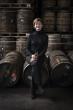 Stephanie MacLeod seated on a barrel, many barrels behind her.
