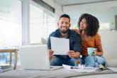 Smiling couple sitting on couch and looking at a piece of paper together