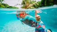 Child giving the "thumbs up" sign while swimming underwater