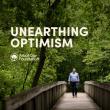 Unearthing Optimism podcast cover shows CEO Dan Lambe looking up while walking down a bridge in the middle of a forest.