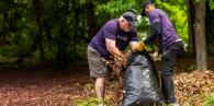 Two Truist volunteers stuffing debris into a bag.