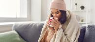 women drinking from a mug wrapped in a hat and blanket