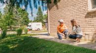 utility worker and homeowner crouched near a home and talking