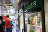 People in a line past a Goodr labeled fridge in a mobile grocery store