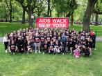 The MAC team of walkers in a park in front of "aids walk new york" sign.