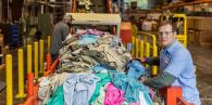 A person next to a line of waste textiles.