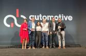 A row of people posed on a stage in front of a sign "Automotive". One holds an award.