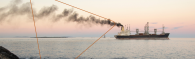 Ship with dark gray smoke coming out of smoke stack