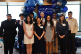 People smiling and standing together under blue balloons