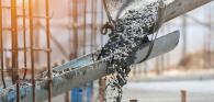 Concrete flowing down troughs at a construction site.