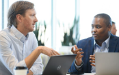 Two people talking while on laptops