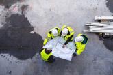 Aerial view of four construction workers overlooking a blueprint.