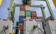 Stacked shipping containers and cranes, power boxes in front.