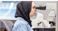 A person looking in a microscope in a lab setting