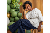 Person sitting on a chair next to green balloons