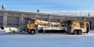 A large de-icing machine outside covered in snow