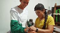 Woman assisting customer in trying on bracelet