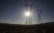 Tall power lines lined up with the sun over a large flat open landscape