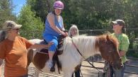 person with special needs riding a horse with support from three other people