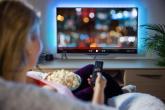 person watching tv and eating popcorn