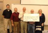 Five people holding an oversized check