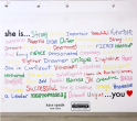 A mural at the Lower East Side Girls Club that says "she is" with many positive adjectives listed in marker below it