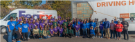 A large group of volunteers posed in front of a FedEx truck and trailer.