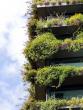 A multi-story building with overflowing plants on every balcony.