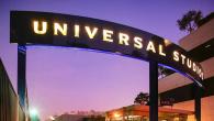 Illuminated "Universal Studios" sign. Buildings and sunset behind it.