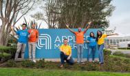 group smiling in front of Applied Materials logo