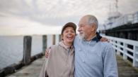 A man and woman shown on a pier in an embrace.