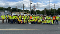 A group on high-vis vests and hard hats posed outside.