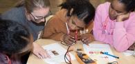 Kids working together with written instructions and electronics, wires and batteries.