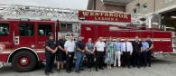 A group posed in front of a fire truck outside.