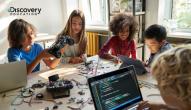 Young people work at a table on computers and electronics